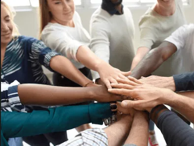 Mãos de pessoas diversas unidas no centro de uma roda